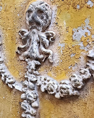 Detailed view of a weathered plaster appliqué against ochre tones, inspiration for the Tuscan Ochre & Ash Architectural Panel Finish by Amy Howard At Home.