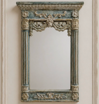 Decorative mirror with ornate frame on a wall with decorative molding.