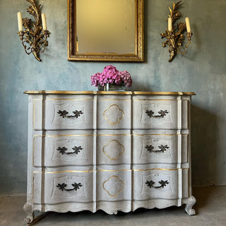 Vintage-style dresser with gold accents against a textured wall.