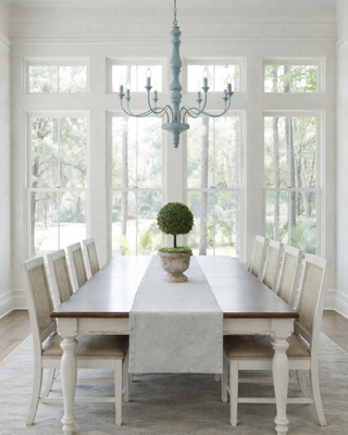 Bright dining room with a long table, chairs, and a chandelier painted in LuxeLacquer in color Stormy Sky by Amy Howard at Home.