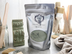 A package of Toscana Milk Paint in 'Topiary' color, with a background featuring brushes and a decorative ornament.
