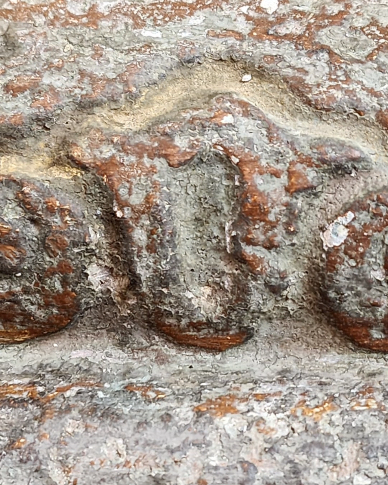 Weathered Chapel Patina finish close-up showing limestone grey, oxidized green, and earthen rust tones on decorative carved surface