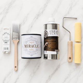 Amy Howard At Home Miracle Paint bundle with One Hour Miracle Paint, brush, Clean Slate degreaser, and foam roller on marble background