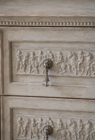 Close up of Amy Howard At Home Relief Decorative Mould WoodCast classical frieze appliqué applied to drawer fronts on a whitewashed antique dresser with brass and glass drawer pulls