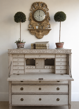 Amy Howard At Home Renaissance Decorative Mould WoodCast appliqué detail applied to the trim of a painted antique secretary desk, styled with topiaries, a gilded clock, and antique books