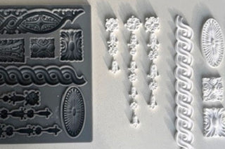 Amy Howard At Home Rolling Coin Decorative Silicone Mould shown side by side with finished CeramiCast ornamental castings including border strips, medallions, and decorative appliqué details