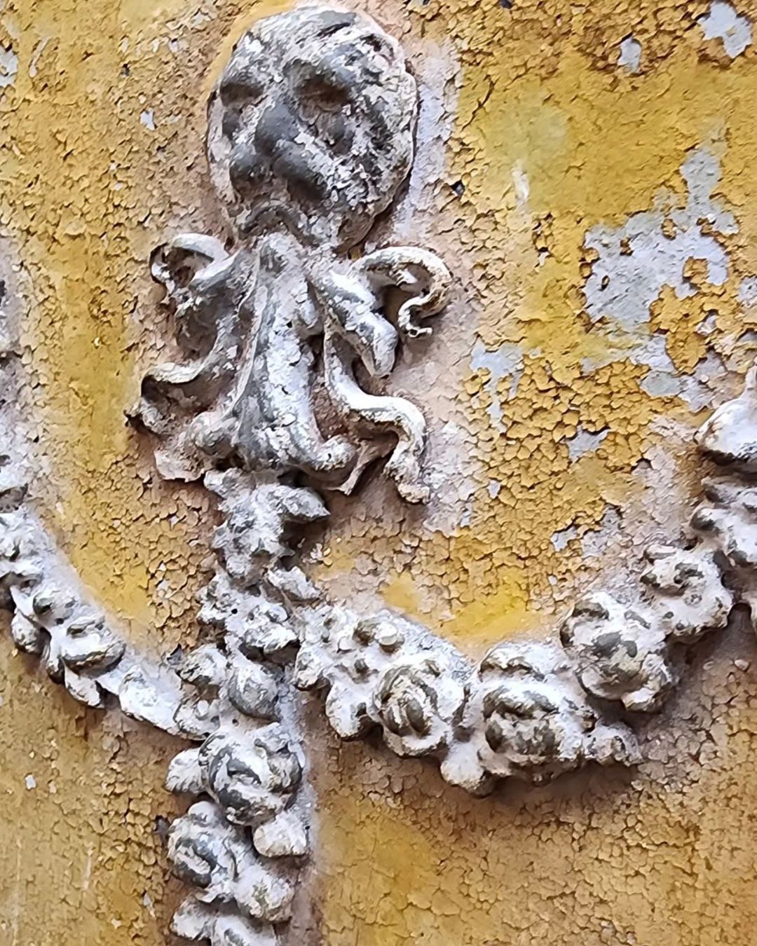 Detailed view of a weathered plaster appliqué against ochre tones, inspiration for the Tuscan Ochre & Ash Architectural Panel Finish by Amy Howard At Home.