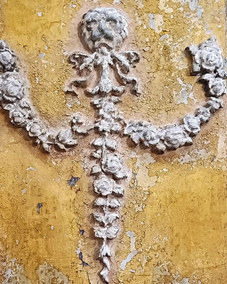 Close up of an aged decorative appliqué on sun baked ochre, inspiration for the Tuscan Ochre & Ash Architectural Panel Finish by Amy Howard At Home.
