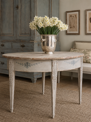 Gustavian demilune table with a crackled aged patina finish and hand-painted floral details, styled with white narcissus in a silver champagne bucket
